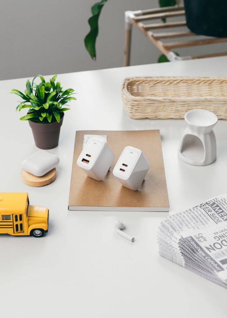 Chargers arranged on a white desk beside a plant
