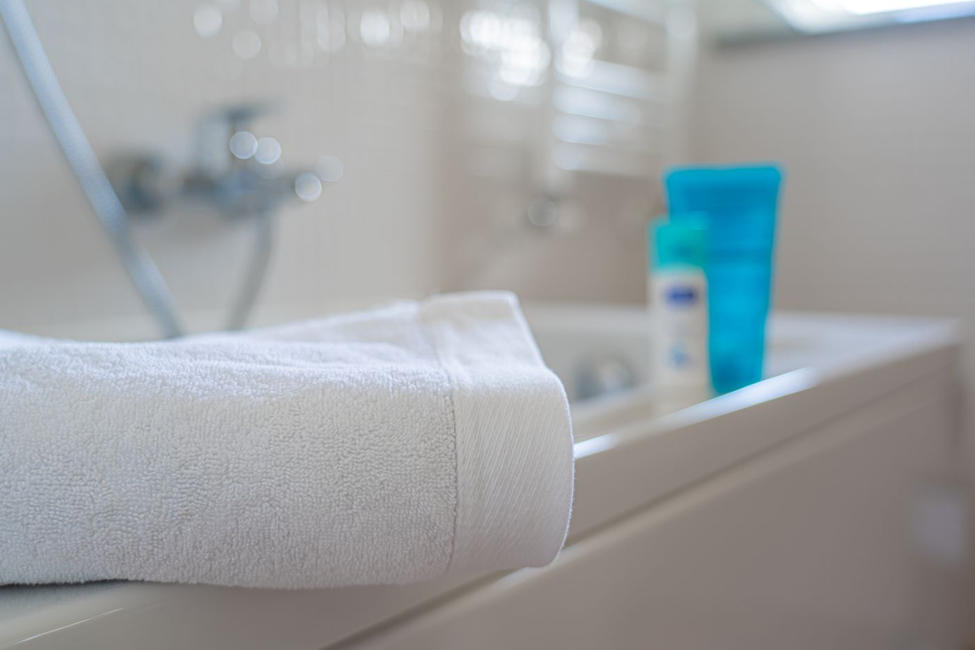 Folded white bath towel resting on a bathtub rim