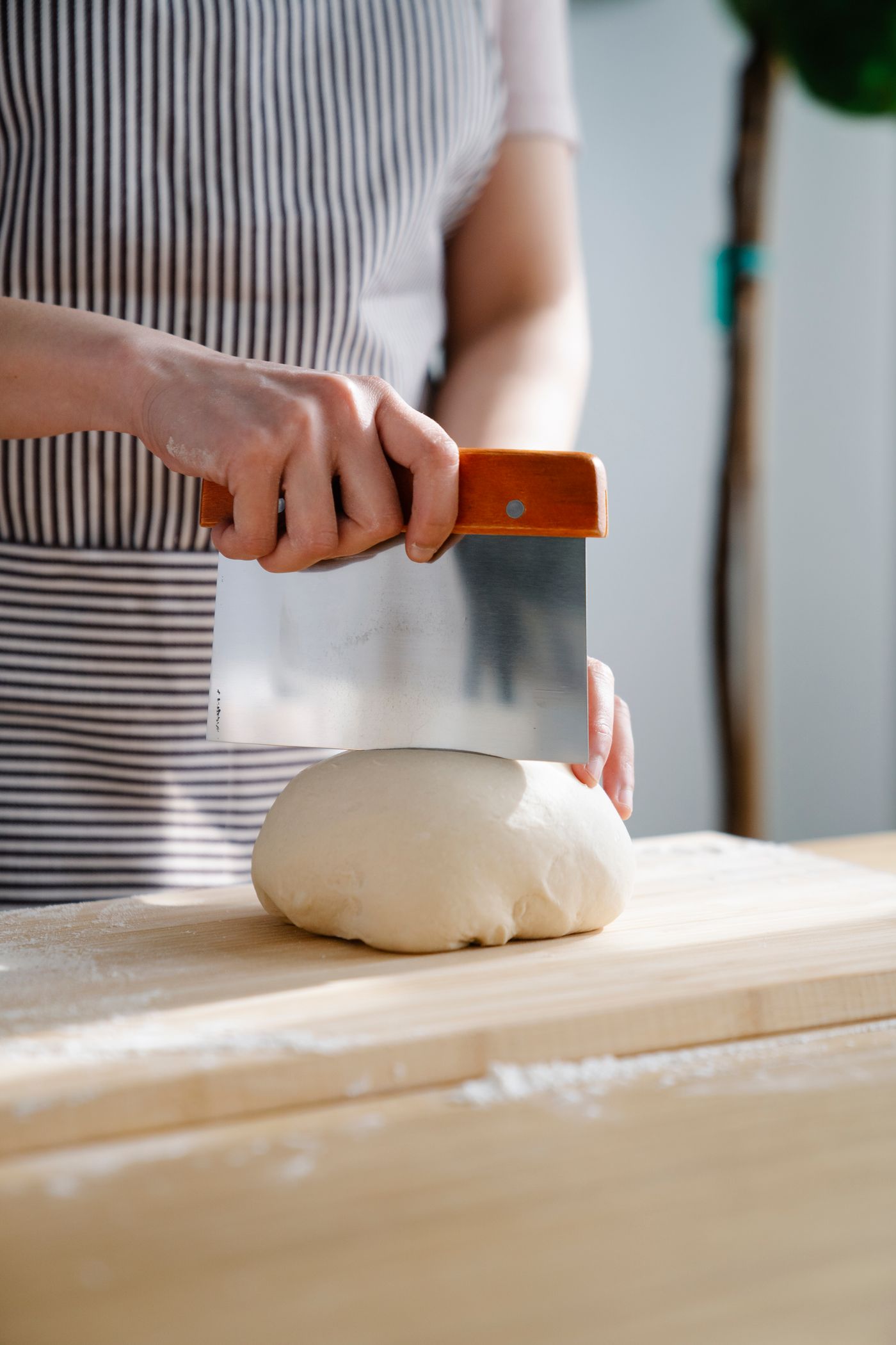 Person dividing dough on a wooden board