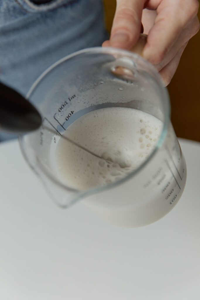 Cup of milk being held during coffee preparation