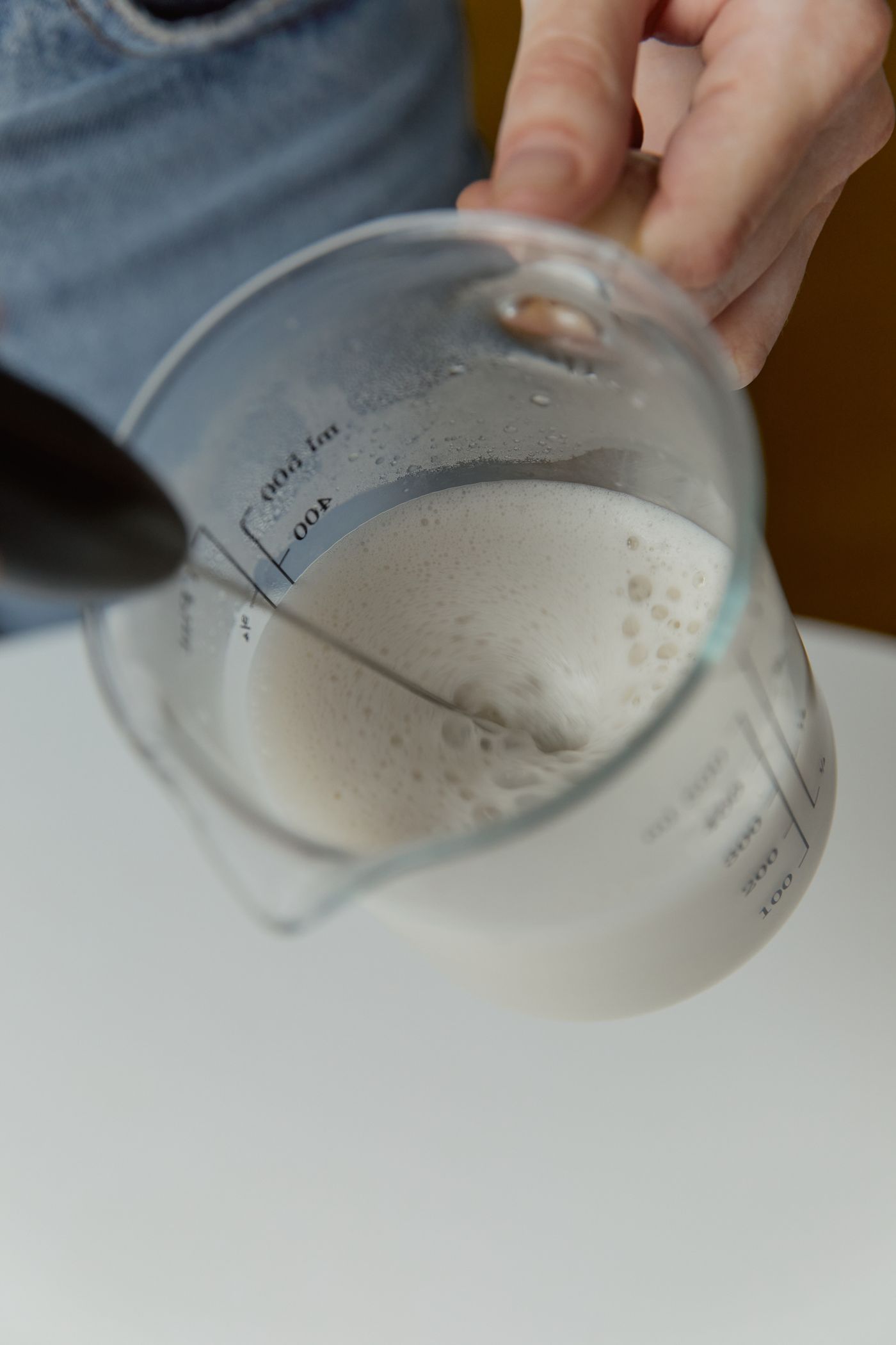 Cup of milk being held during coffee preparation
