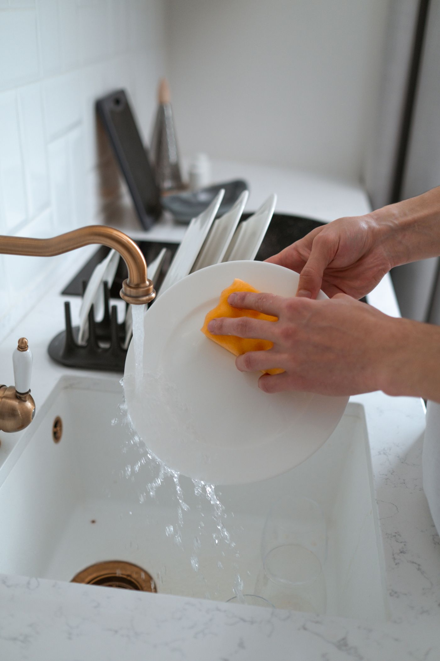 Person washing a plate in a kitchen sink