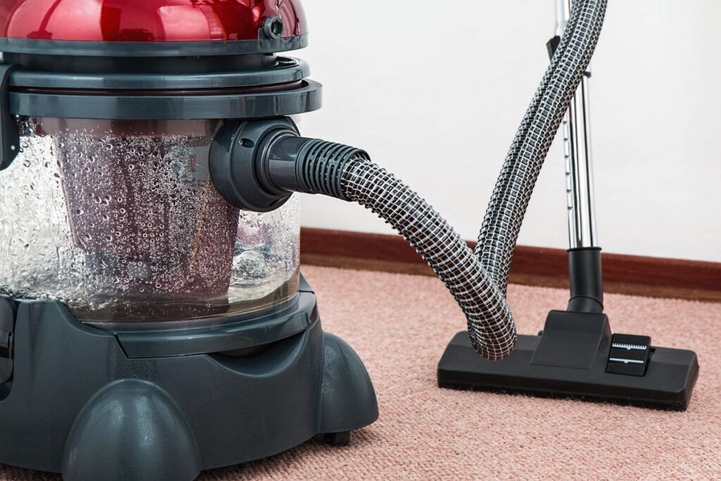 Black and red canister vacuum cleaner on carpet