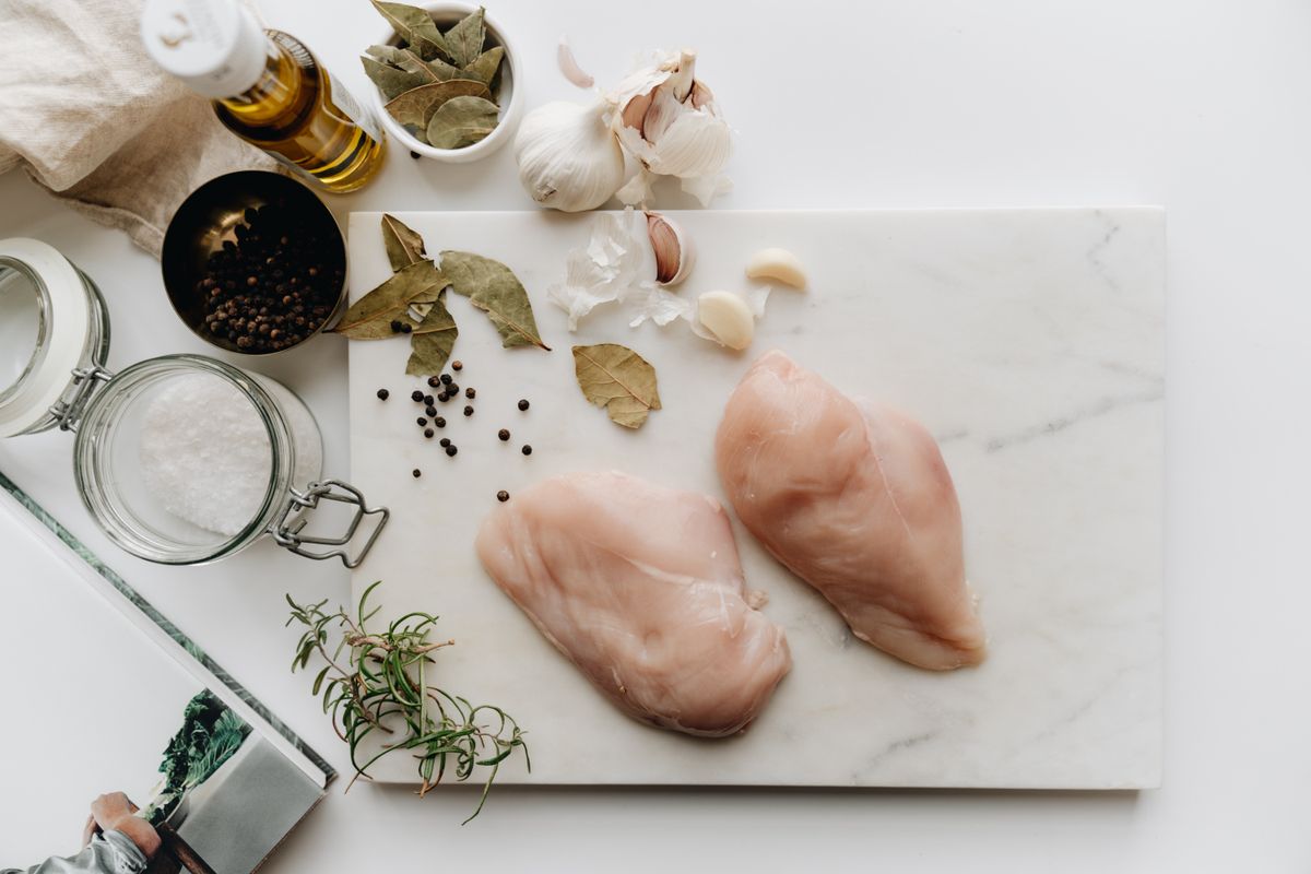 Raw chicken breasts with herbs on a preparation board
