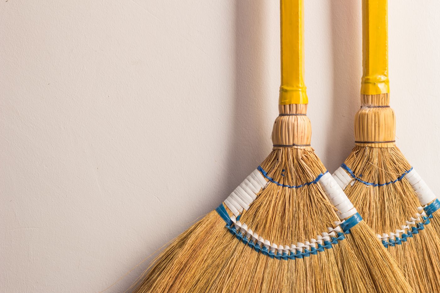 Two traditional brooms resting against a wall