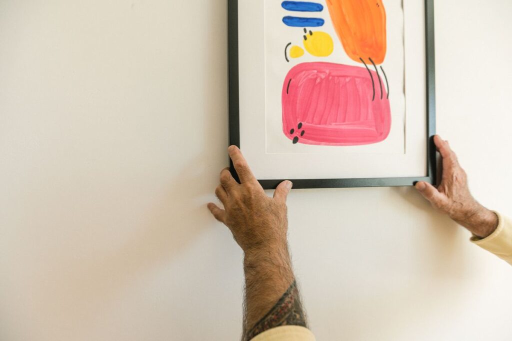 Person positioning framed artwork on a wall