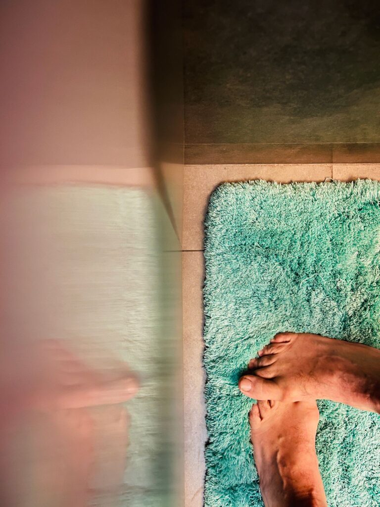 Person standing on a green bathroom mat