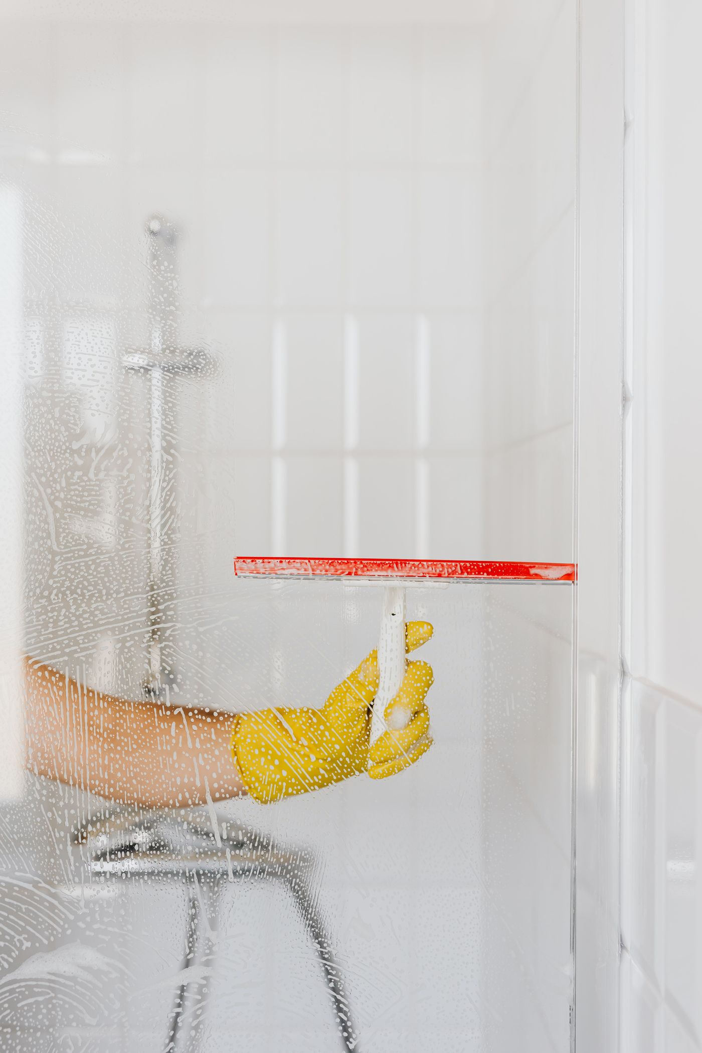 Person cleaning shower glass with a squeegee