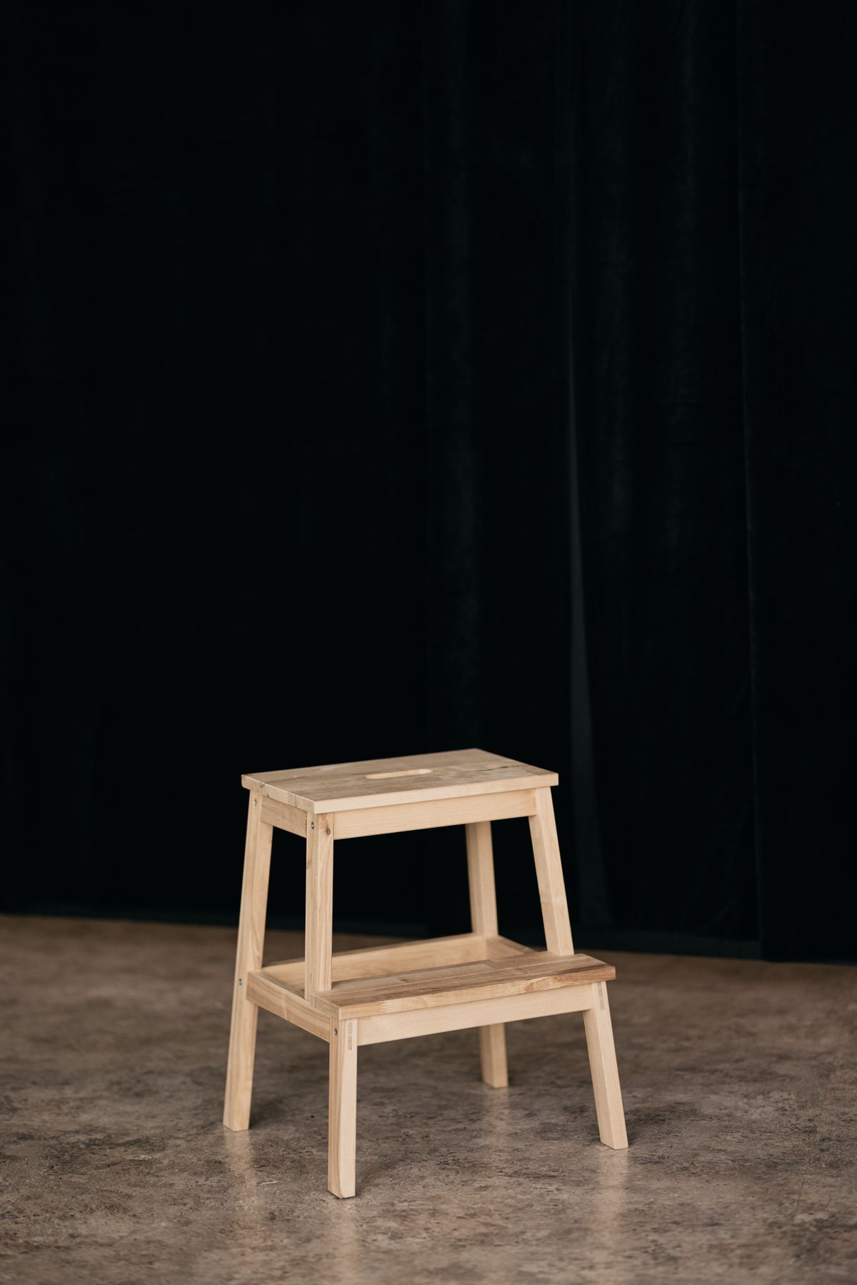 Wooden step stool against a dark background