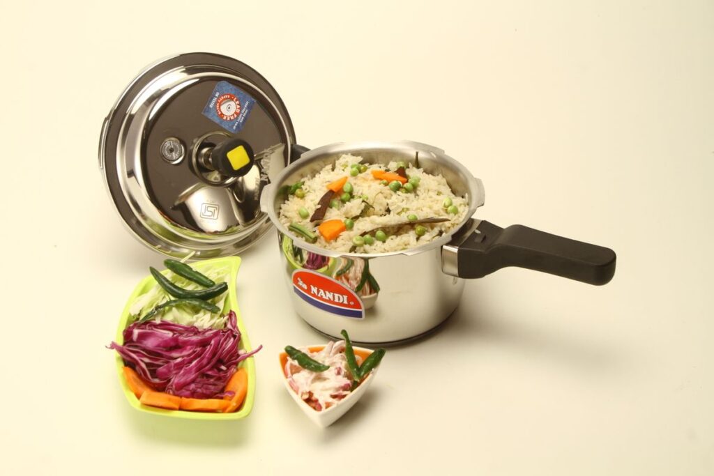 Pressure cooker beside a prepared rice and vegetable meal