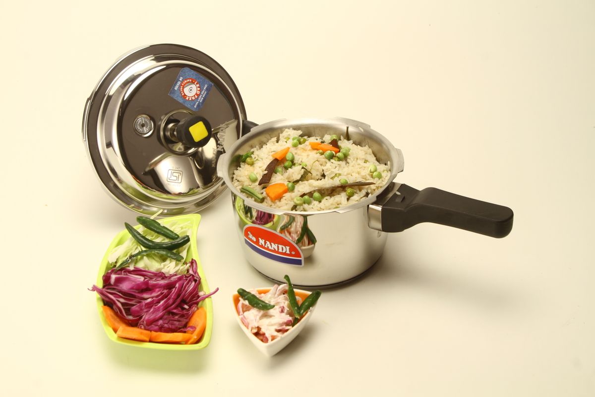 Pressure cooker beside a prepared rice and vegetable meal
