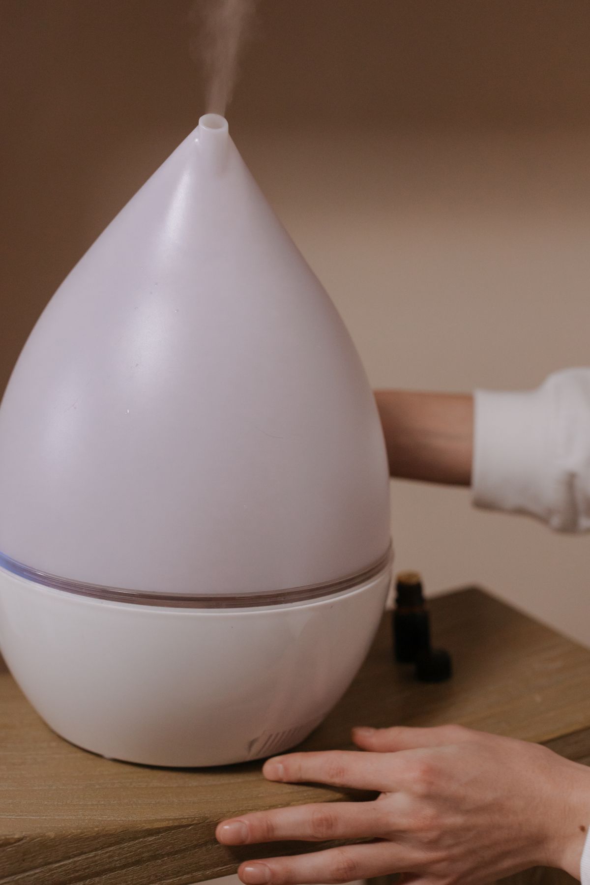 Person adjusting a mist-producing device on a wooden surface