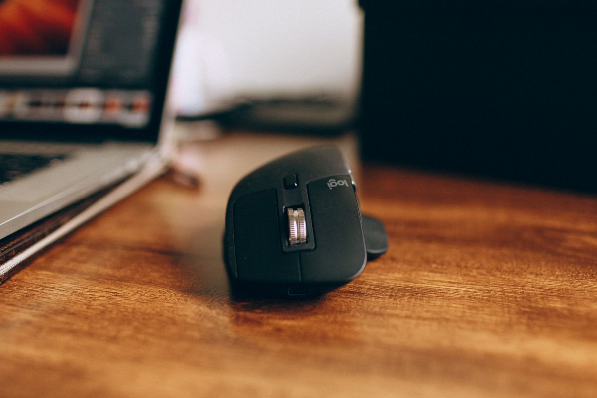 Wireless mouse beside a laptop on a wooden desk