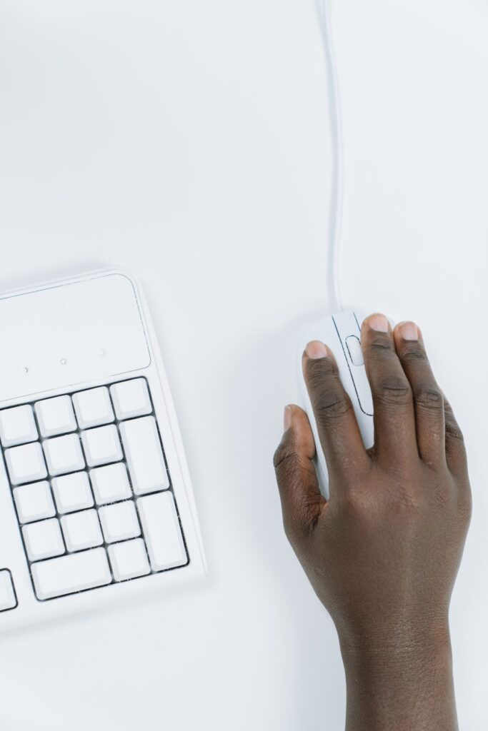Hand using a white mouse beside a keyboard