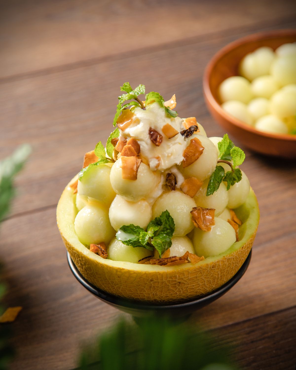 Melon balls served in a bowl with mint and cream