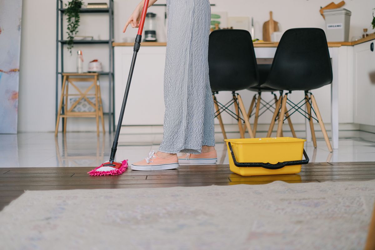 Person mopping a kitchen floor beside a bucket