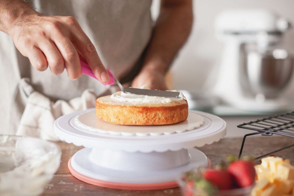 Person spreading frosting on a cake