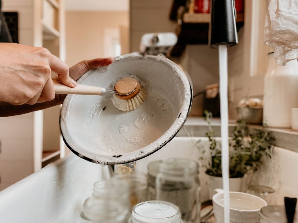 Person washing a bowl with a dish brush