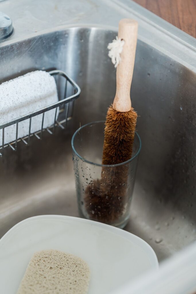 Cleaning brush resting in a glass beside a sink