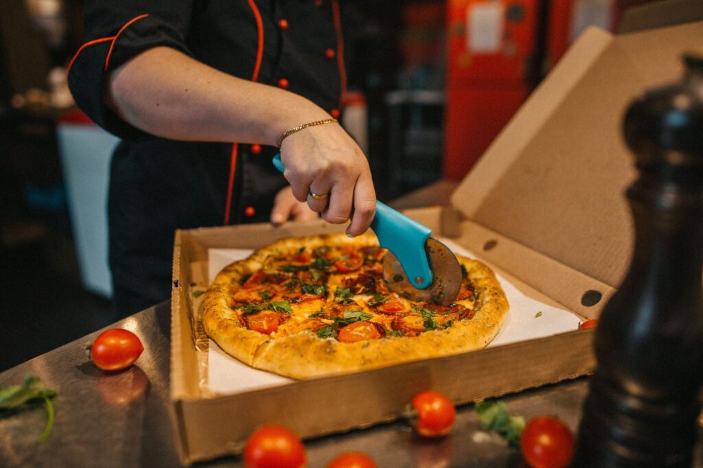 Person slicing pizza with a wheel cutter