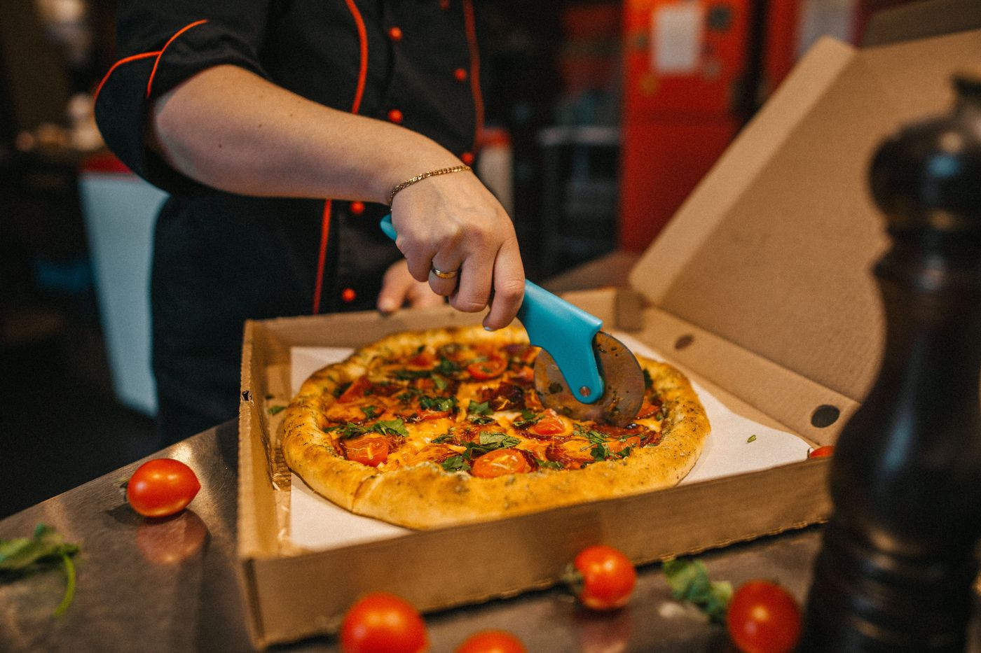 Person slicing pizza with a wheel cutter