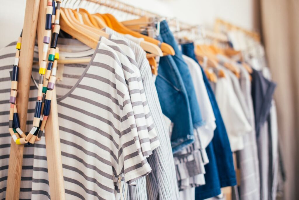 Clothing on wooden hangers inside a wardrobe