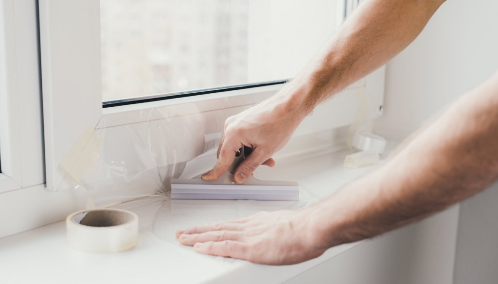 Clear removable window insulation film being applied in an apartment