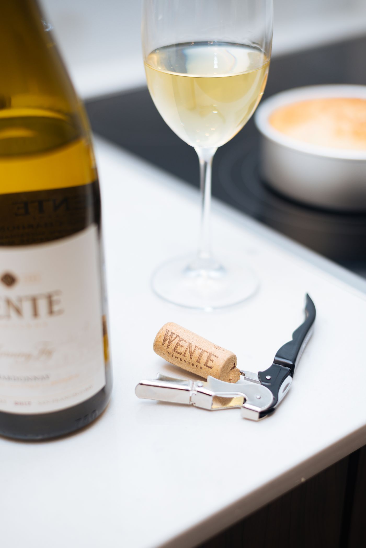 Wine glass and bottle beside a corkscrew on a table